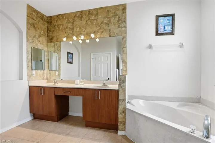 Bathroom with double vanity, a garden tub, and light tile patterned flooring