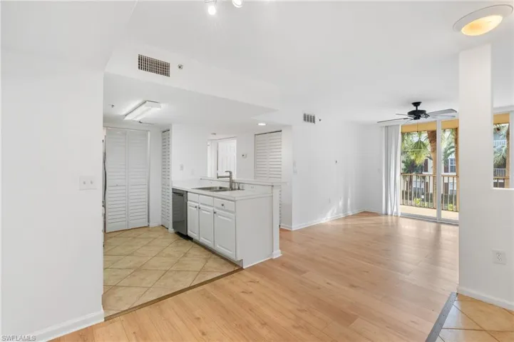 Kitchen with sink, white cabinetry, stainless steel dishwasher, ceiling fan, and light hardwood / wood-style floors