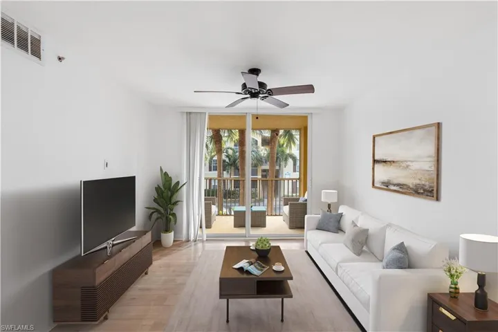 Living room featuring a wall of windows, light wood-style floors, visible vents, and ceiling fan, Virtually Staged