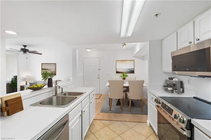 Kitchen with light countertops, light tile patterned floors, appliances with stainless steel finishes, white cabinetry, and a sink, Virtually Staged