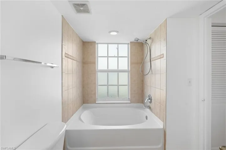 Bathroom with tiled shower / bath combo and toilet