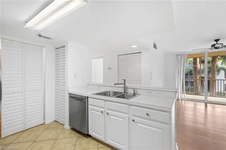 Kitchen with sink, dishwasher, ceiling fan, white cabinetry, and kitchen peninsula