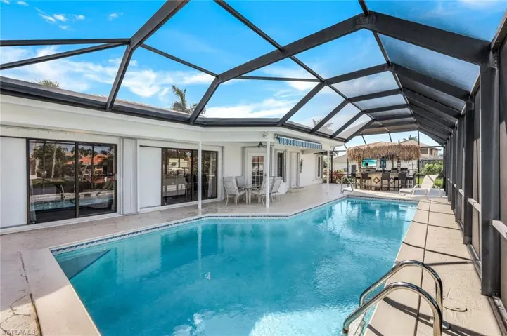 View of swimming pool with a patio area and glass enclosure