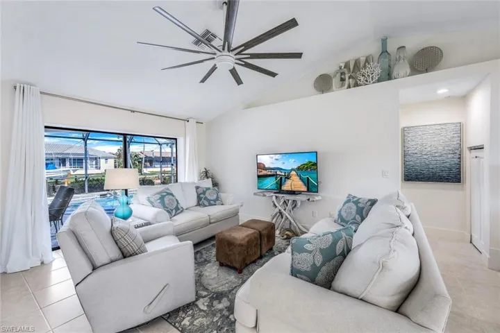 Living room with ceiling fan, light tile floors, and lofted ceiling