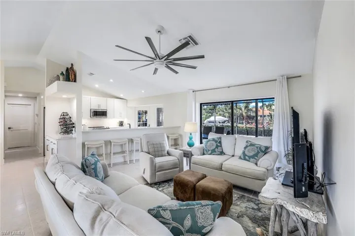Tiled living room with ceiling fan and lofted ceiling