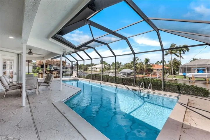 View of swimming pool with a patio, glass enclosure, and ceiling fan