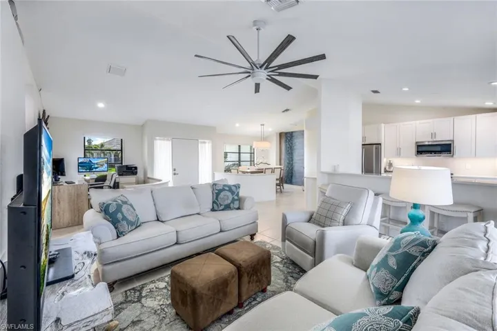 Living room with plenty of natural light, ceiling fan, light tile floors, and lofted ceiling