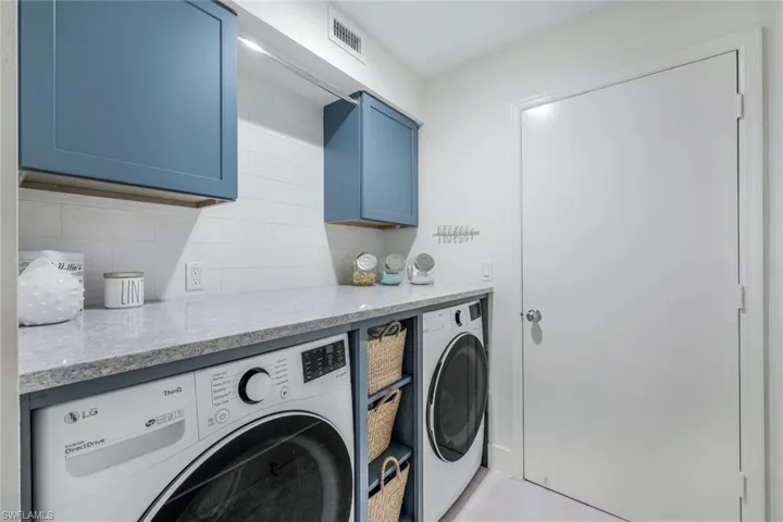 Laundry area with washer and clothes dryer and cabinets