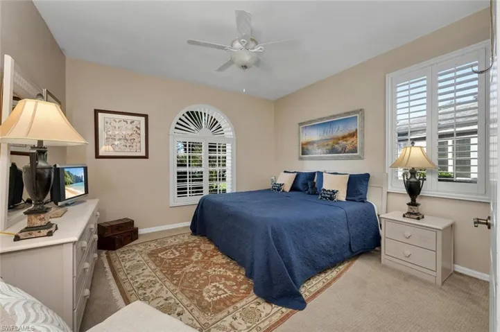 Carpeted bedroom with multiple windows and ceiling fan