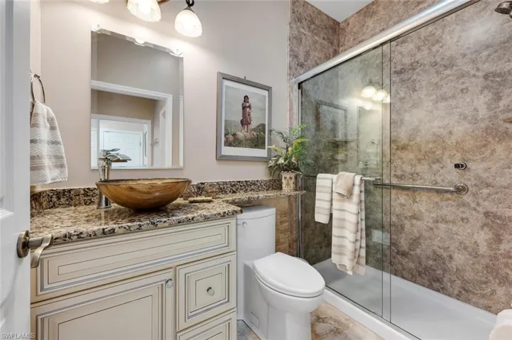 Bathroom with vanity, a shower with shower door, and toilet