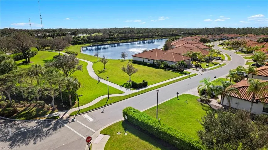 Birds eye view of property featuring corner lot, walking path, sidewalks and beautiful lake views.
