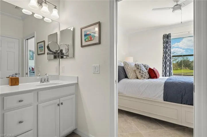 Primary Bathroom featuring double vanity, a walk-in tiled shower, ornamental molding, and tile floors.