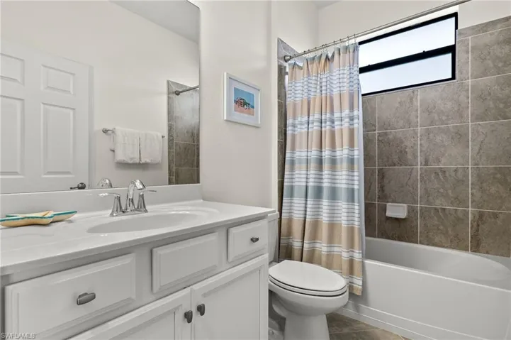 Guest bathroom featuring a white vanity, a tiled shower/bath combo and tile floors.