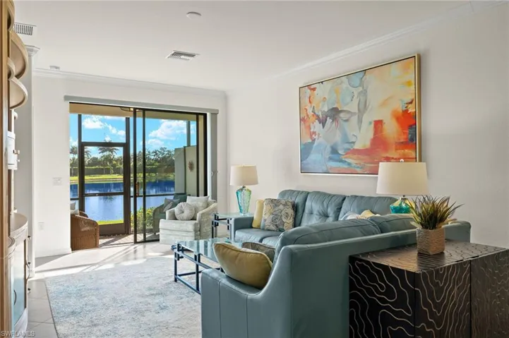 Fully furnished living room featuring tranquil lake views, crown molding, and tile floors