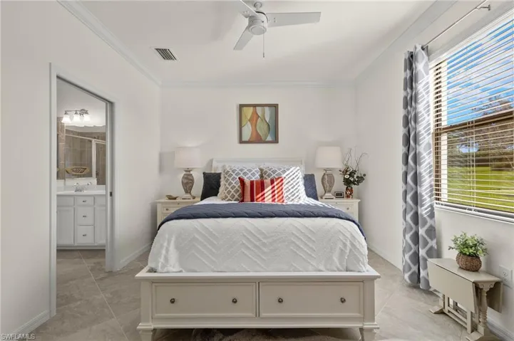 Primary Bedroom featuring connected bathroom, crown molding, light tile floors, ceiling fan and lake views.