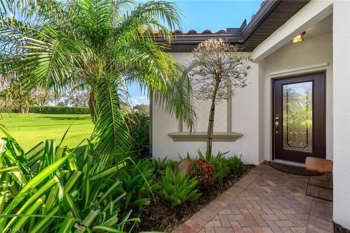 Entry with an ornamental lead glass door and lush landscaping.