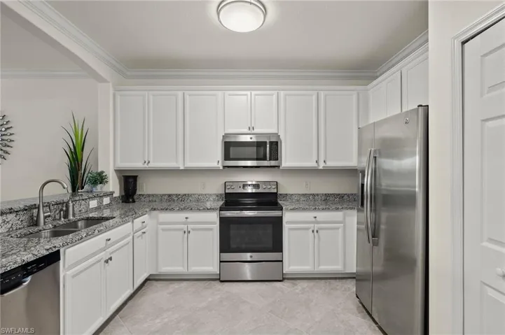 Spacious kitchen with stainless steel appliances, granite counters, white cabinets and a pantry