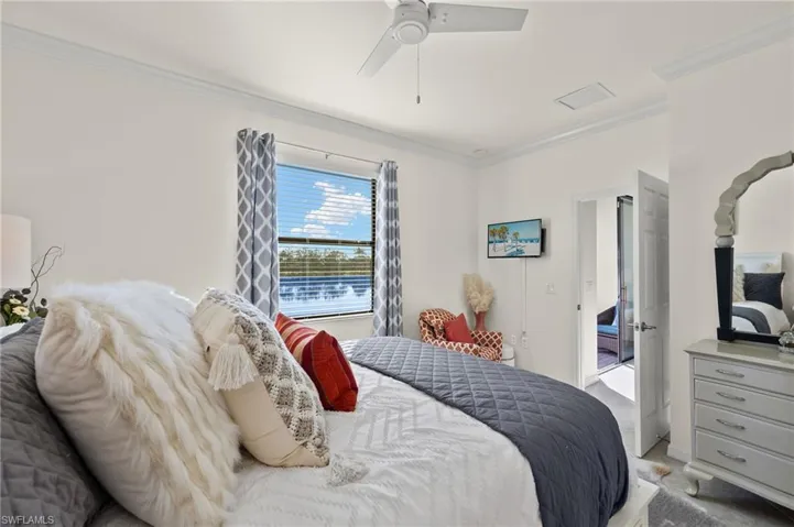 Primary Bedroom featuring sitting area, crown molding, light tile floors, ceiling fan and lake views.