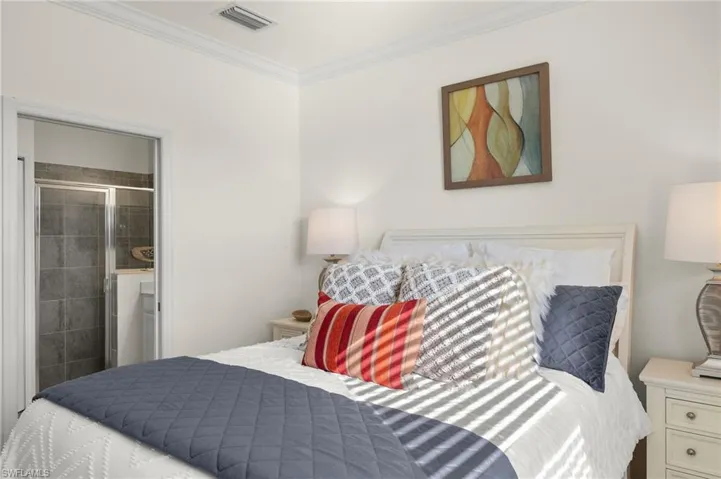 Primary Bedroom featuring connected bathroom, crown molding, light tile floors, ceiling fan and lake views.