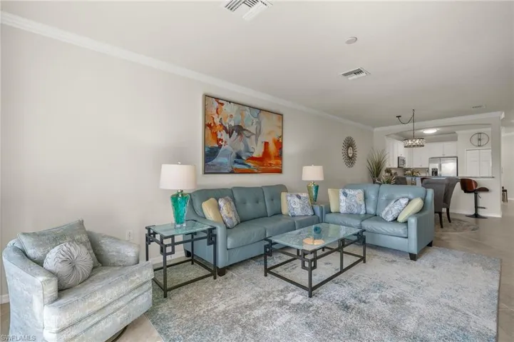 Fully furnished Living room with crown molding, artwork, tile floors and decorative area rug.