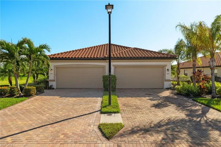 Mediterranean villa featuring a two car attached garage an large driveway with pavers.