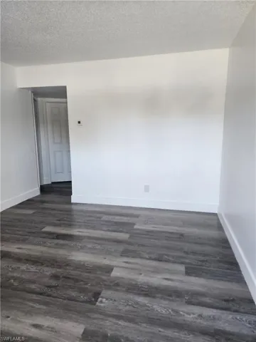 Unfurnished room featuring a textured ceiling and dark wood-style flooring