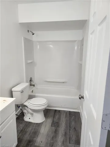 Bathroom featuring vanity, dark wood-style floors, and  shower combination