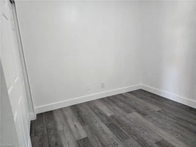 Unfurnished room featuring dark wood-type flooring and baseboards