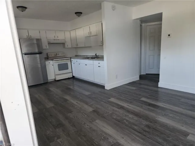 Kitchen featuring freestanding refrigerator, electric range, light countertops, white cabinets, and a textured ceiling