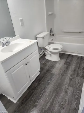 Full bath with vanity, dark wood-style flooring, and  shower combination