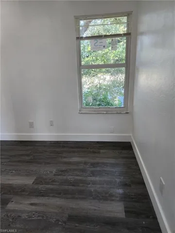 Unfurnished room with dark wood-style flooring and baseboards