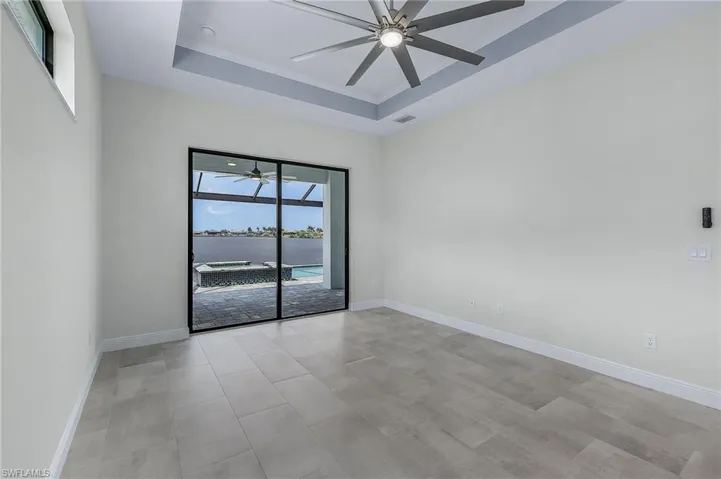 Empty room featuring ceiling fan and a tray ceiling