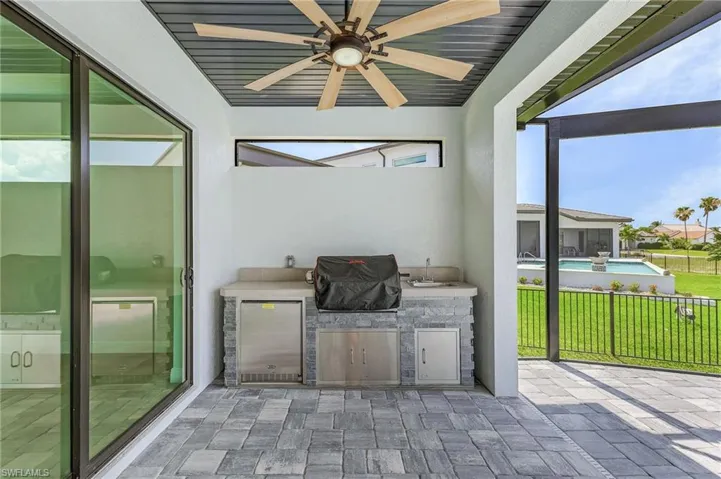 View of terrace with an outdoor kitchen, a pool, and ceiling fan