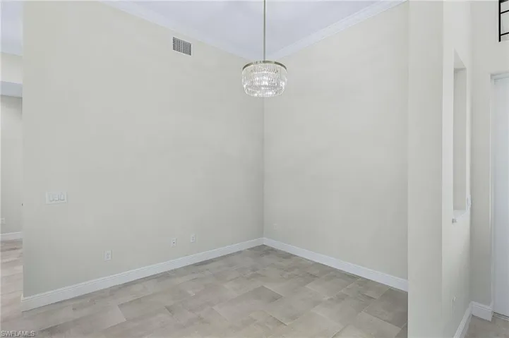 Empty room featuring ornamental molding and an inviting chandelier