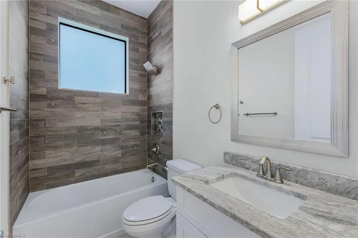 Full bathroom with tiled shower / bath, vanity, and toilet