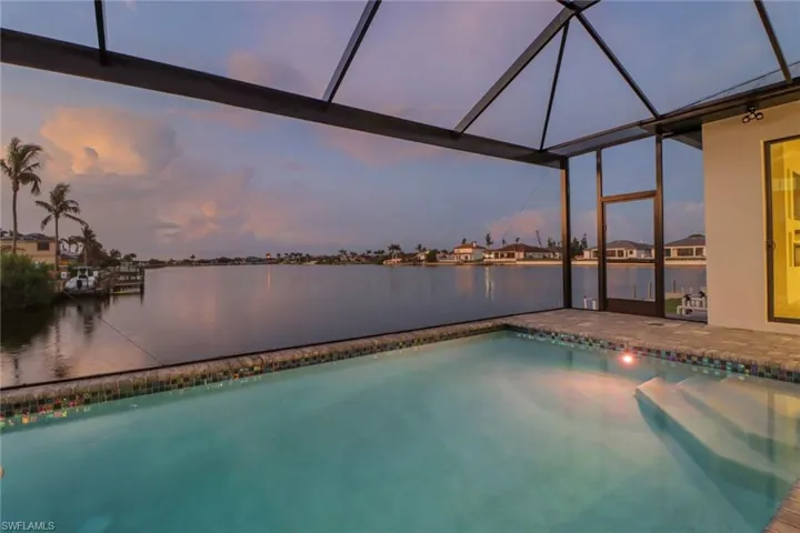 Pool at dusk with a lanai and a water view