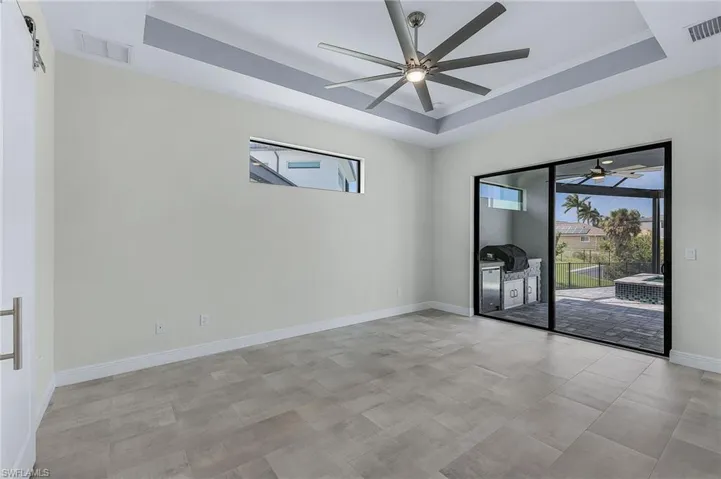 Tiled spare room with a raised ceiling and ceiling fan