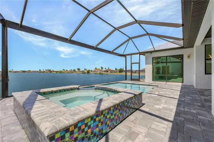 View of pool featuring a water view, a lanai, an in ground hot tub, and a patio