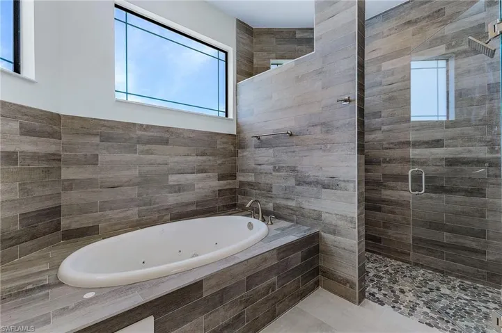 Bathroom with tile walls, a wealth of natural light, and plus walk in shower