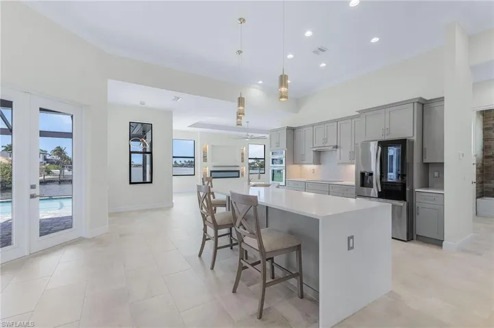 Kitchen featuring stainless steel appliances, decorative light fixtures, a kitchen island, backsplash, and a breakfast bar