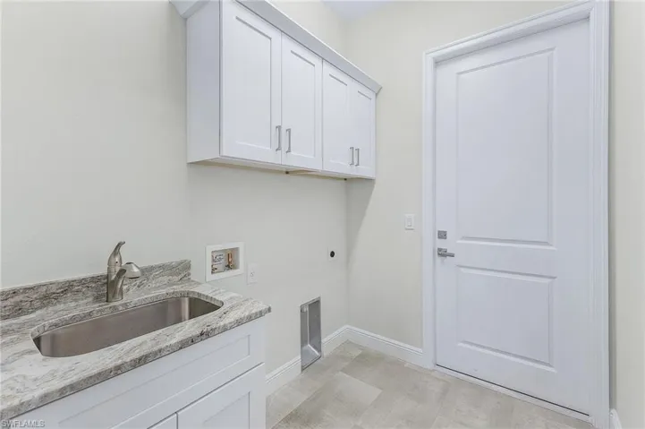Laundry area featuring cabinets, light hardwood / wood-style flooring, washer hookup, sink, and hookup for an electric dryer