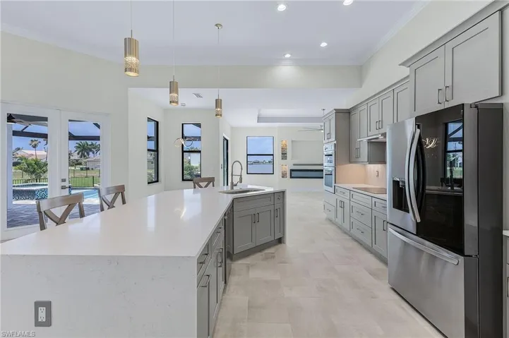 Kitchen featuring hanging light fixtures, gray cabinetry, a center island with sink, appliances with stainless steel finishes, and sink
