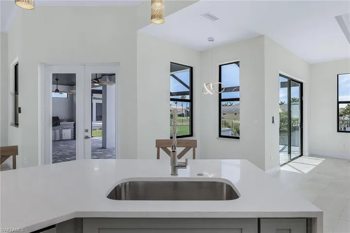 Kitchen featuring light stone countertops, ceiling fan, decorative light fixtures, light tile floors, and sink