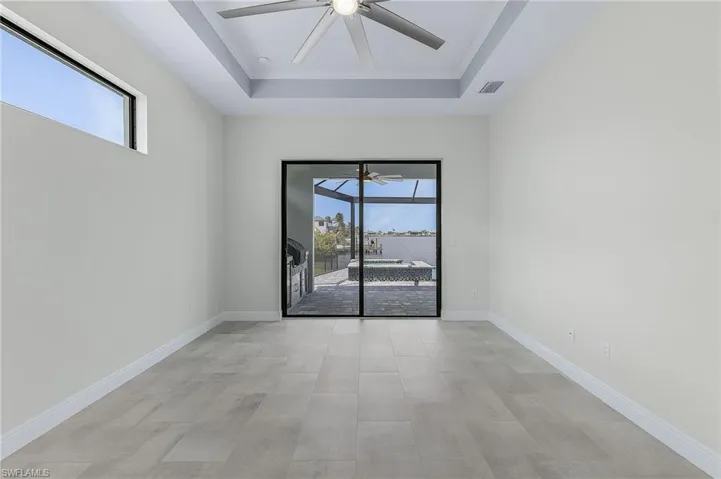 Empty room featuring plenty of natural light, ceiling fan, and a raised ceiling