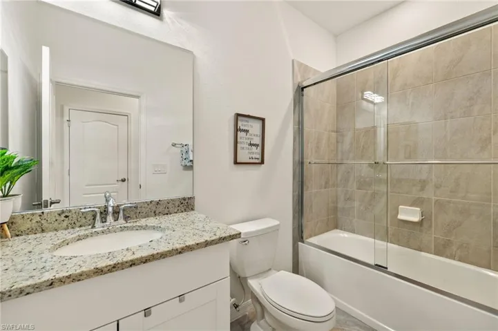 Full bathroom with shower / bath combination with glass door, vanity, and toilet