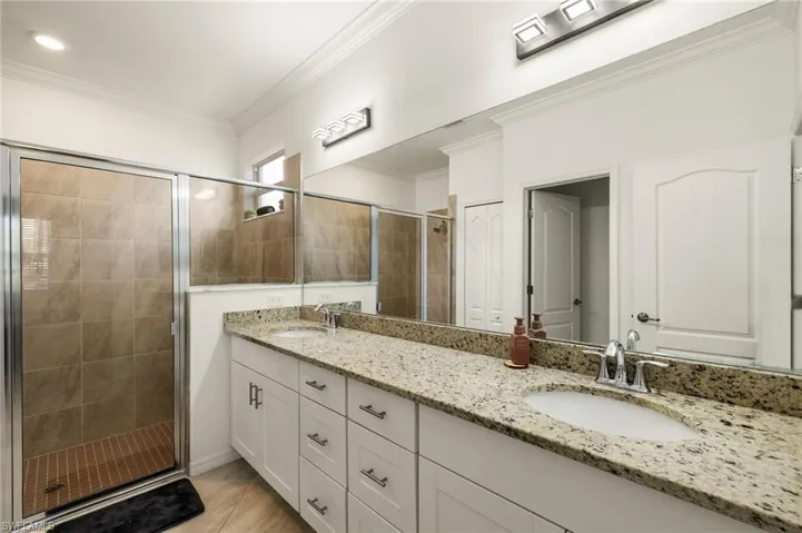 Full bathroom with ornamental molding, a sink, and a shower stall