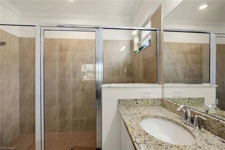 Full bathroom featuring a stall shower, ornamental molding, and vanity