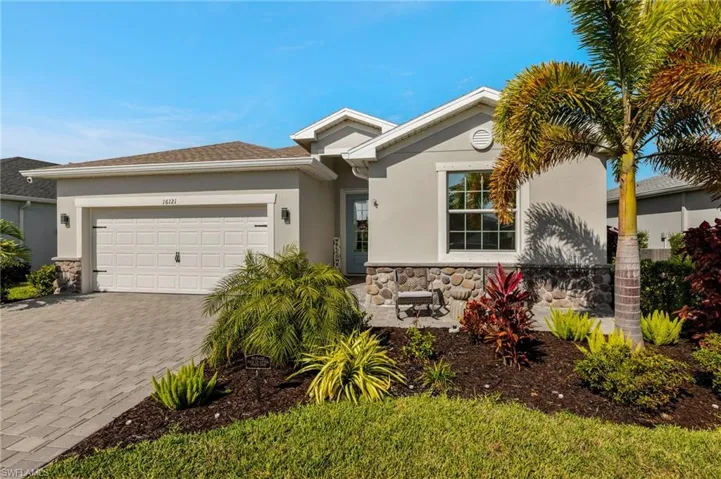 View of front of property featuring a garage, stone siding, decorative driveway, and stucco siding