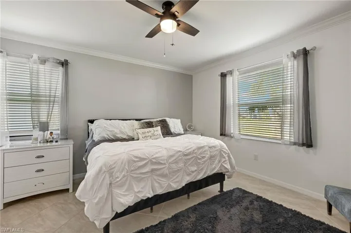 Bedroom with baseboards, light tile patterned floors, a ceiling fan, and crown molding