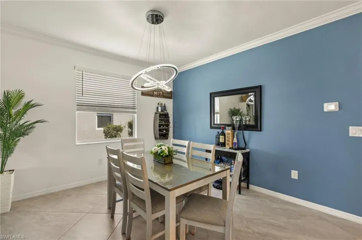 Dining room with a chandelier, crown molding, baseboards, and light tile patterned floors